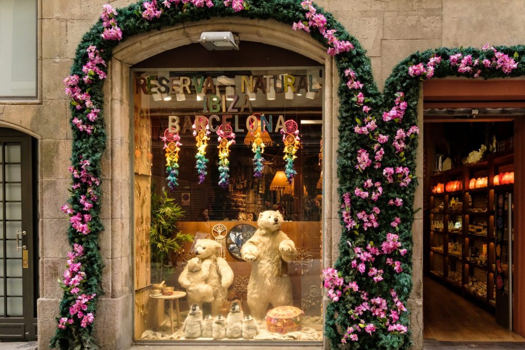 Beautifully decorated shop window of polar bears and penguins on display. A floral garland wraps around the perimeter of the shop window and entrance.