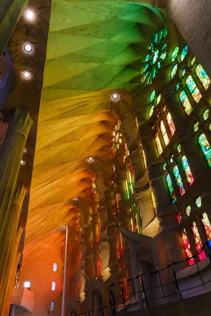 Warm orange and green light streaming in through the stained glass windows of La Sagrada Familia.